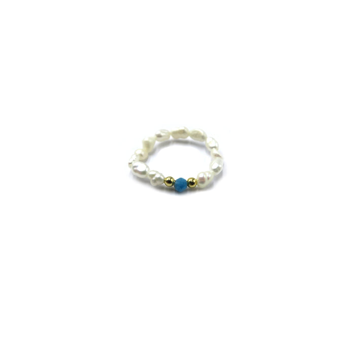 A delicate beaded ring featuring irregular white pearls, two small gold spacer beads, and a central blue bead, displayed on a clean white background.